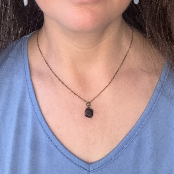 Necklace with a pendant worn by a person in a blue shirt