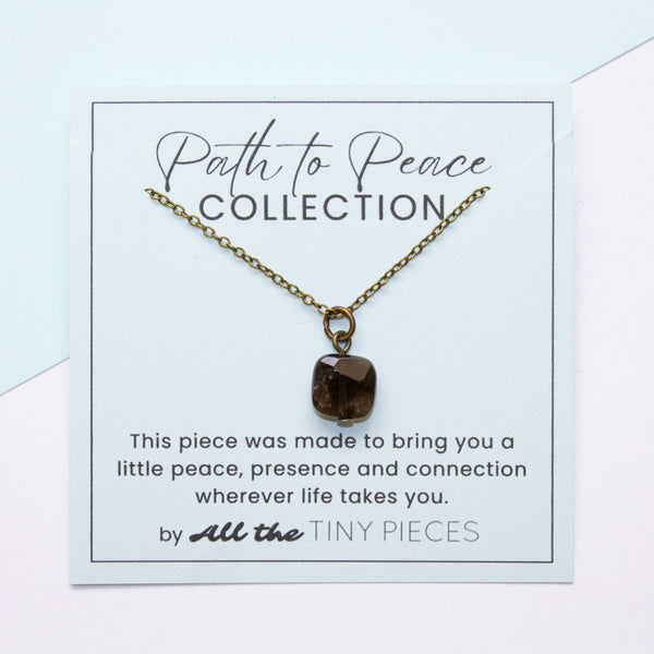 Necklace with a smoky quartz pendant on a 'Path to Peace Collection' card with text.