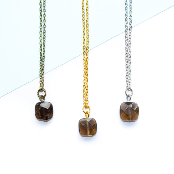 Three necklaces with square smoky quartz gemstones on a light blue and white background