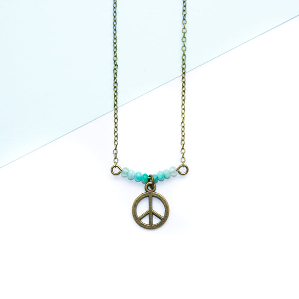Necklace with peace symbol pendant and amazonite beads on a light blue and white background