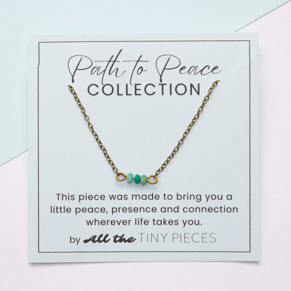Necklace with amazonite beads on a 'Path to Peace Collection' card with text.