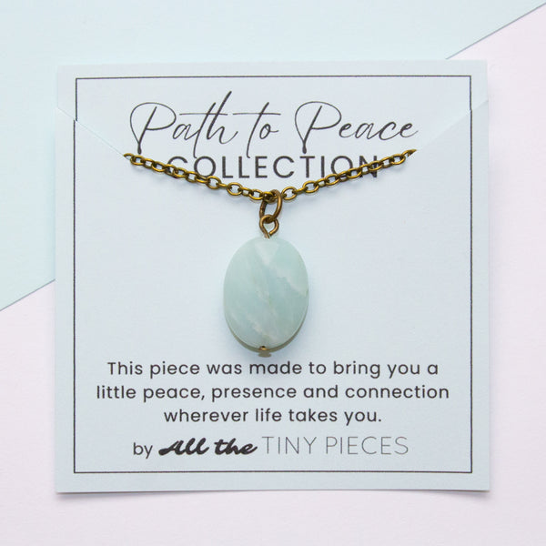 Necklace with an amazonite pendant on a 'Path to Peace Collection' card with text.