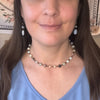 Person wearing an amazonite beaded necklace with earrings, against a neutral background