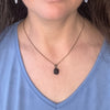 Necklace with a pendant worn by a person in a blue shirt