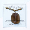 Necklace with a smoky quartz pendant on a card with text, displayed against a white background.