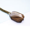 smoky quartz faceted pendant on a chain against a white background
