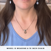 Person wearing a necklace with a peace symbol pendant, text indicating chain length.