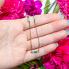 Gold chain necklace with amazonite beads held in a hand against pink flowers