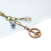 Brass peace sign charm on a chain with beads against a white background