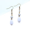 Pair of earrings with blue lace agate beads and brass hooks on a light blue background
